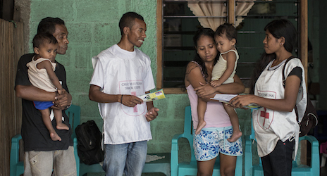 L-R: Richardo Bento, Lorenzo Lurdes, Clementa Bento and Floriana Carolina Pieres discuss ways to prevent dengue from spreading around their home. Volunteers from Cruz Vermelha Timor-Leste's Dili branch visits a home as part of a dengue outreach education program.